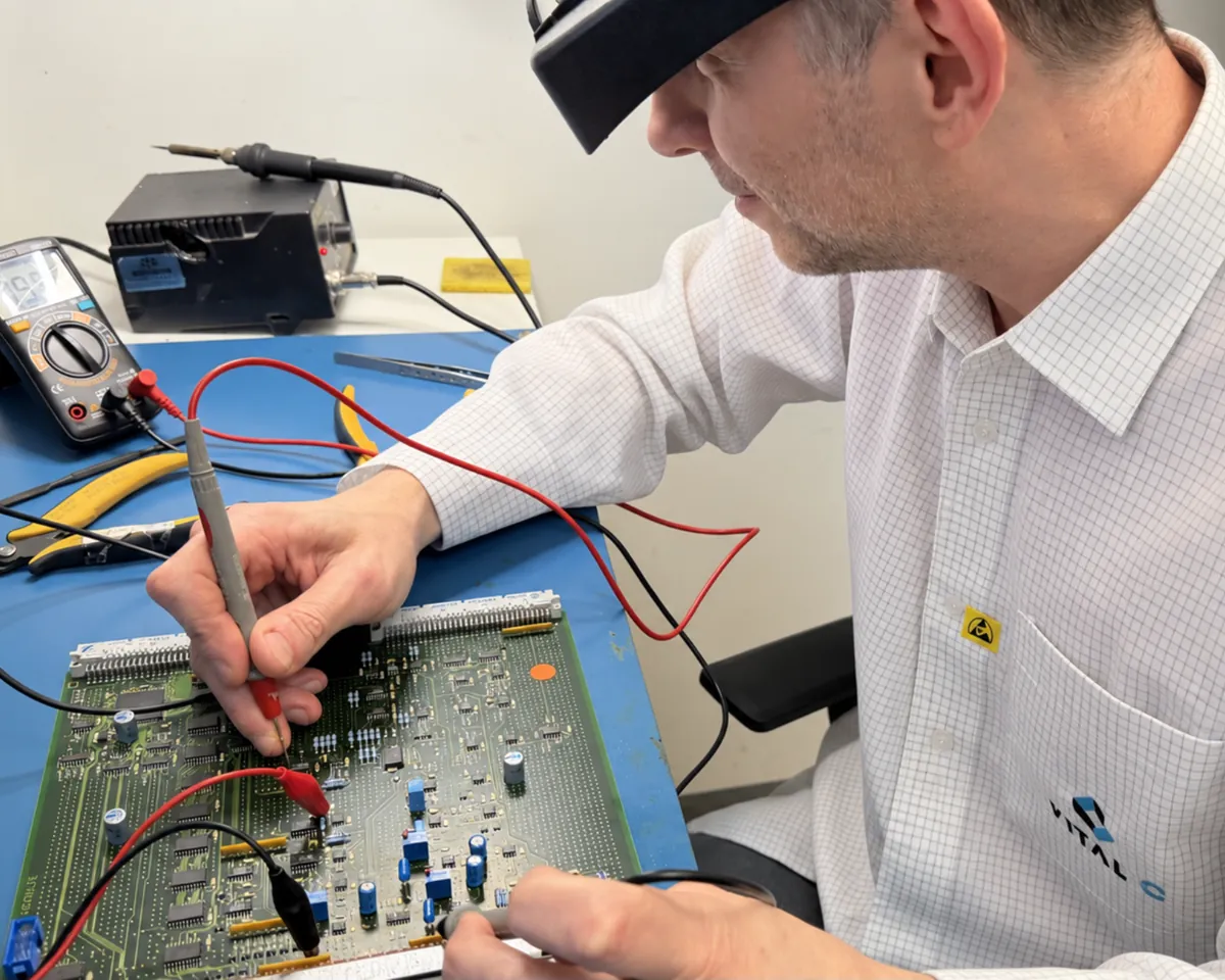 Técnico da Vital C testa uma placa eletrônica de equipamento médico com multímetro na bancada