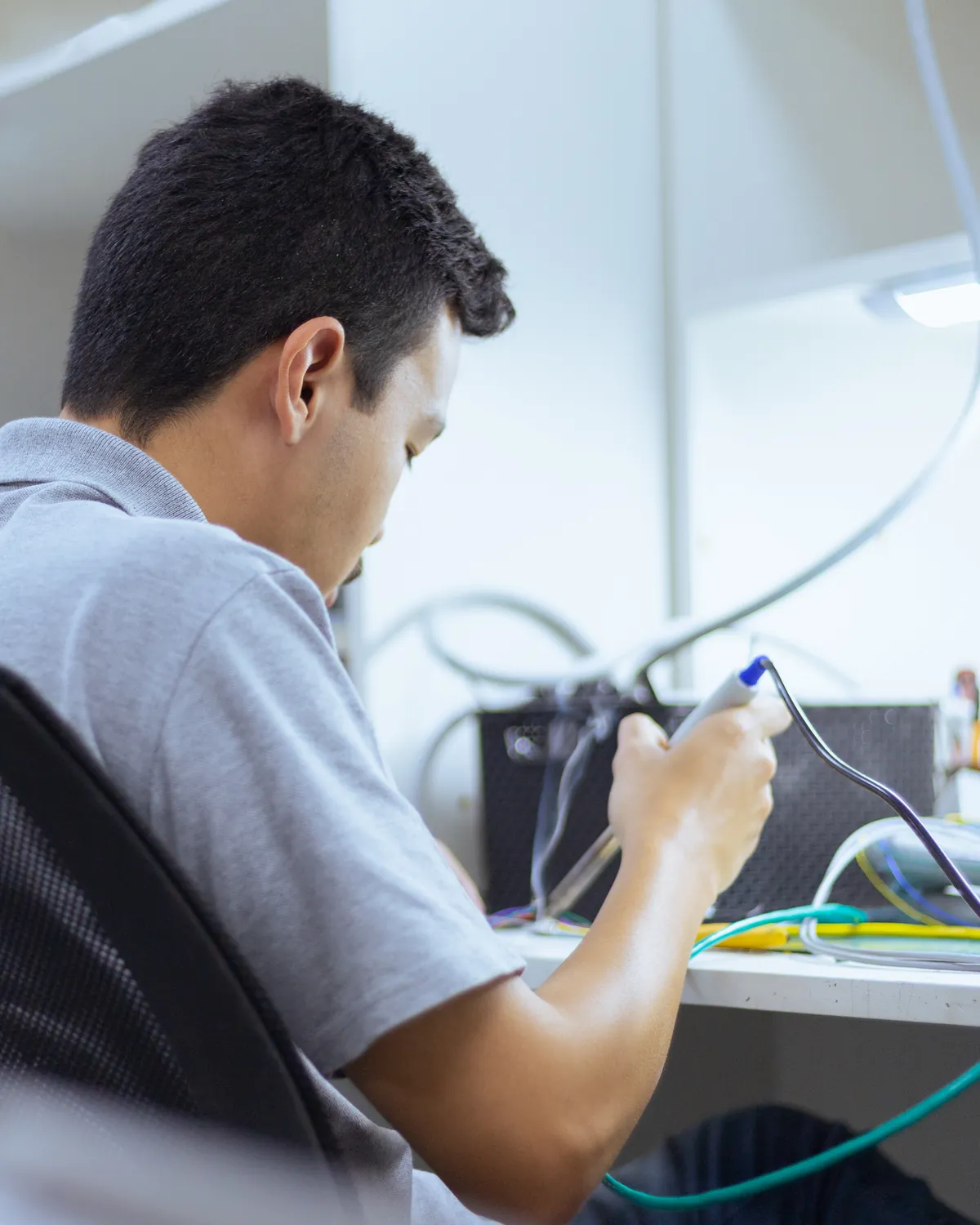 Técnico da Vital C faz uma solda na bancada do laboratório técnico