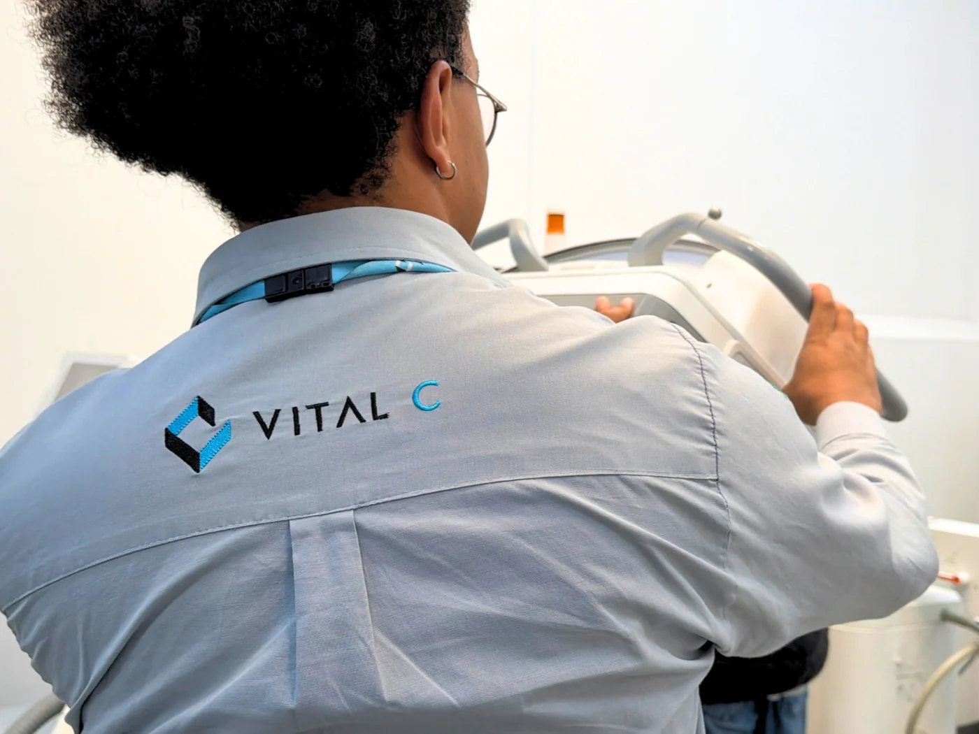 Técnico da Vital C, com o logo da empresa na camisa, posiciona um arco cirúrgico no laboratório